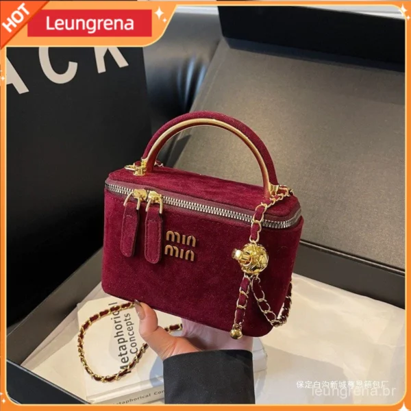 Bolsa marrom de veludo com alça dourada e zíper metálico dourado.