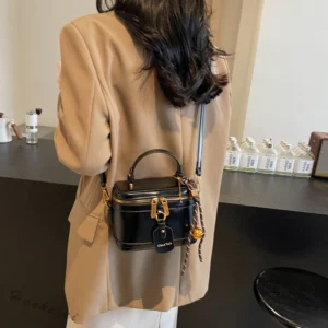 Modelo usando uma bolsa de ombro feminina, na cor preta, com detalhe em corrente, destacando a aparência elegante e o tamanho da bolsa.